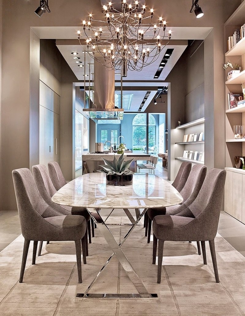 A dining room with a marble-look table and taupe upholstered chairs